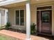 Charming front porch featuring a decorative door, brick floor, and seating area with ferns at 103 Aisling Ct, Cary, NC 27513