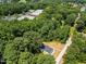 Aerial view showing house enveloped by mature trees, nearby commercial building and access via gravel driveway at 1065 Shuford Rd, Wake Forest, NC 27587