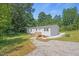 Charming single-story home with gravel driveway and a wooden porch, nestled amongst mature trees at 1065 Shuford Rd, Wake Forest, NC 27587