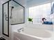 A bathroom featuring a tub and a glass enclosed shower with a bright window at 1103 Mallory Ln, Durham, NC 27713