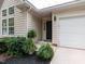 Welcoming front entrance featuring a dark door, lush landscaping, and an attached garage at 1103 Mallory Ln, Durham, NC 27713
