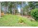 Lush backyard with tall trees, tiered planting beds, and play structure at 1120 Colonial Club Rd, Wake Forest, NC 27587