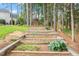 Landscaped backyard with tiered retaining wall and playhouse surrounded by mature trees at 1120 Colonial Club Rd, Wake Forest, NC 27587