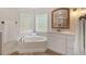 Bright bathroom with a soaking tub, glass block windows, and a vanity with a decorative mirror at 1120 Colonial Club Rd, Wake Forest, NC 27587