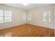 Sunny bedroom with hardwood floors, three windows, and neutral paint, ready for personalization at 1120 Colonial Club Rd, Wake Forest, NC 27587