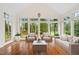 Inviting sunroom features hardwood floors, stylish furniture, and large windows showcasing picturesque golf course views at 1120 Colonial Club Rd, Wake Forest, NC 27587