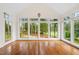 Bright sunroom featuring hardwood floors, a cross decoration, and a wall of windows overlooking lush greenery at 1120 Colonial Club Rd, Wake Forest, NC 27587