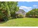 Spacious, grassy backyard with a view of the home's rear exterior and surrounding trees and landscaping at 1153 Litchborough Way, Wake Forest, NC 27587