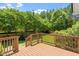 View of the wood deck overlooking a fenced backyard, with beautiful green landscaping and mature trees at 1153 Litchborough Way, Wake Forest, NC 27587