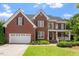 Charming two-story brick home featuring a manicured lawn and attached two-car garage at 1153 Litchborough Way, Wake Forest, NC 27587