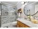 Beautiful bathroom featuring gray tiled shower and a round mirror above a marbled countertop vanity at 11619 Appaloosa W Run, Raleigh, NC 27613