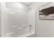 Clean bathroom featuring a bathtub with a shower, white tile, and decorative artwork at 117 S Woodstone Dr, Archer Lodge, NC 27527