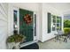 Close-up of front door with colorful wreath, vibrant potted flowers, and a cozy bench at 121 Trevor Ridge Dr, Holly Springs, NC 27540