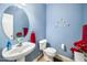 Stylish half-bathroom with a modern sink, blue walls, decorative art, and red accents at 121 Trevor Ridge Dr, Holly Springs, NC 27540