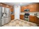 Modern kitchen with stainless steel refrigerator, oak cabinets, and checkerboard tile flooring at 121 Trevor Ridge Dr, Holly Springs, NC 27540