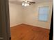 This bright bedroom features hardwood floors, a ceiling fan, and a large window for natural light at 1225 Fairlane Rd, Cary, NC 27511