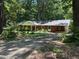 Charming red brick single story home with covered porch, set amongst a densely treed and landscaped front yard at 1225 Fairlane Rd, Cary, NC 27511