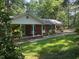 Charming brick home with a covered porch and rocking chairs surrounded by a wooded lot at 1225 Fairlane Rd, Cary, NC 27511