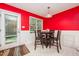 Bright dining room with a dark wood table, contrasting red and white walls, with an exit to the yard at 1261 Grovewood Dr, Clayton, NC 27520
