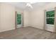 A cozy bedroom features neutral walls, carpeting, a ceiling fan and dual windows with views of lush greenery at 136 Vireo Ln, Hillsborough, NC 27278