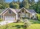 Charming exterior of home with manicured lawn, flowering bushes, two-car garage and beautiful architectural features at 136 Vireo Ln, Hillsborough, NC 27278
