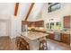 Well-lit kitchen with island seating, stainless appliances, wooden cabinets, and farmhouse sink under large windows at 136 Vireo Ln, Hillsborough, NC 27278