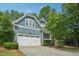 View of blue two-story home showcasing garage, established landscaping, and traditional architectural details at 1419 Endgame Ct, Wake Forest, NC 27587