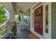 Inviting front porch with rocking chairs, brick columns, and a ceiling fan next to a deep red front door at 149 N Serenity Hill Cir, Chapel Hill, NC 27516