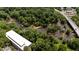 Aerial view shows mature trees surrounding a building with a modern roof and an adjacent gently flowing river at 1500 River Mill Dr # 101, Wake Forest, NC 27587