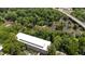 An aerial view shows mature trees surrounding a building with a modern roof and adjacent to a flowing river at 1500 River Mill Dr # 101, Wake Forest, NC 27587
