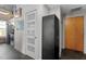 Hallway with a modern white door, black storage cabinet, and a view into the kitchen area at 1500 River Mill Dr # 101, Wake Forest, NC 27587