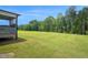 The back yard with a grassy lawn and a tree line in the distance at 1505 Willow Landing Way, Willow Springs, NC 27592