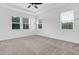 Large bedroom featuring a tray ceiling, three windows, a ceiling fan, and neutral carpet at 1505 Willow Landing Way, Willow Springs, NC 27592