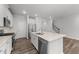 Kitchen with white cabinetry, stainless steel appliances, and large quartz island near a staircase at 156 Velvet Ridge Way, Garner, NC 27529