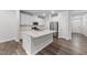 Bright kitchen featuring white cabinets, stainless appliances, and a quartz island, next to exterior and interior doors at 156 Velvet Ridge Way, Garner, NC 27529