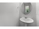 Minimalist powder room with a pedestal sink, round mirror, and soft natural light creating a clean aesthetic at 156 Velvet Ridge Way, Garner, NC 27529