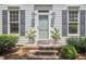 Close-up of a front porch with potted plants, brick steps, and gray trimmed windows at 18 Clearwater Dr, Durham, NC 27707