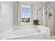 Bright bathroom featuring a soaking tub, shower, and large window with neighborhood views at 1818 Misty Hollow Ln, Apex, NC 27502