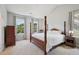 Main bedroom with a four-poster bed, neutral walls, and large windows overlooking trees at 1818 Misty Hollow Ln, Apex, NC 27502