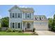 Charming two-story home with light blue siding, gray shutters, and a well-manicured front lawn at 1818 Misty Hollow Ln, Apex, NC 27502