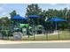 Modern green playground with climbing structures and blue shaded picnic tables at 1891 Frost Dr, Haw River, NC 27258