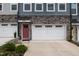 Close up of townhome exterior showing stone accents, garage, colorful front door, and manicured landscaping at 2006 Leo Dr, Apex, NC 27502
