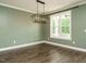 A simple living area with dark wooden floors, light trim, muted green walls, and a hanging light fixture at 2013 Woodbluff Dr, Wendell, NC 27591