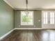 A simple living area with dark wooden floors, light trim, muted green walls, and a hanging light fixture at 2013 Woodbluff Dr, Wendell, NC 27591