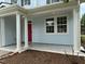 Close up of front porch featuring white columns, a pink door, new landscaping, and patterned concrete walkway at 205 Bog Hill Ln, Cary, NC 27519
