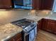 Kitchen featuring stainless steel range, granite countertops, wood floors and cabinetry, and white tile backsplash at 205 Bog Hill Ln, Cary, NC 27519