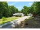 Charming home with a long driveway and outdoor structure, nestled among mature trees at 211 Hills Of The Haw Rd, Pittsboro, NC 27312