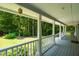Long, covered porch with white railings overlooking a serene backyard with lush trees at 211 Hills Of The Haw Rd, Pittsboro, NC 27312