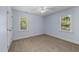 A carpeted bedroom with light blue walls, a ceiling fan, and two windows offering natural light at 2205 Bufflehead Rd, Raleigh, NC 27616