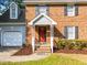 A brick home's front entrance featuring a red door, white columns, and a manicured lawn at 2205 Bufflehead Rd, Raleigh, NC 27616